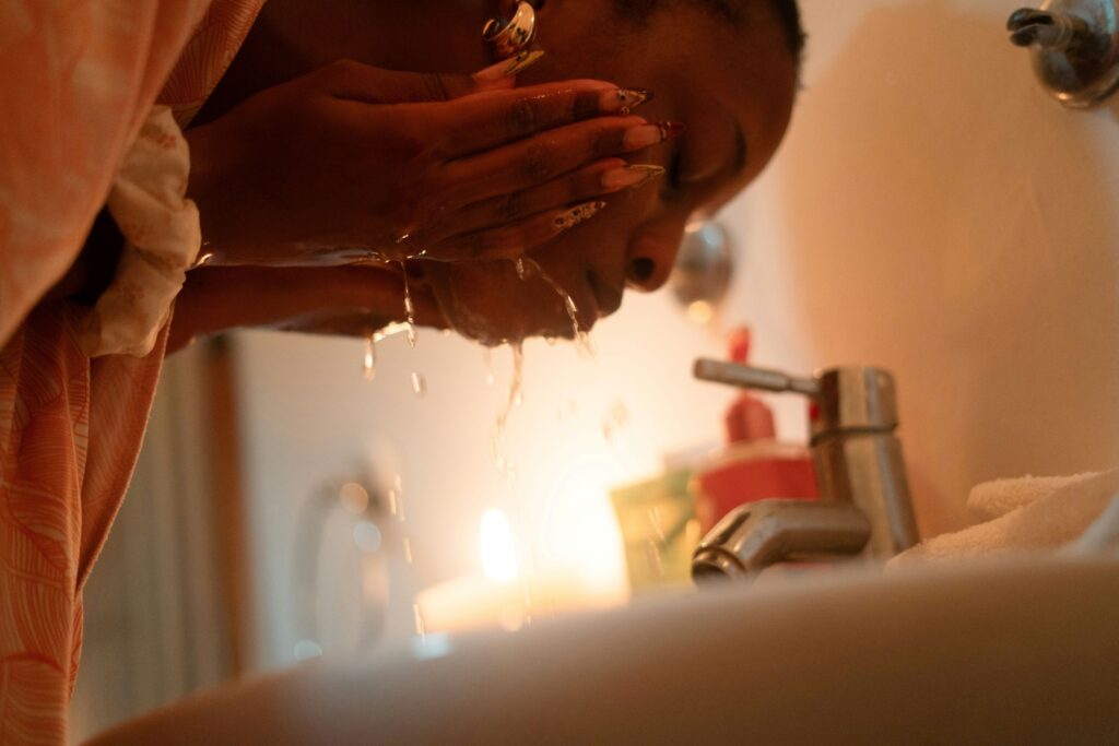 a woman washing her face with cold water
